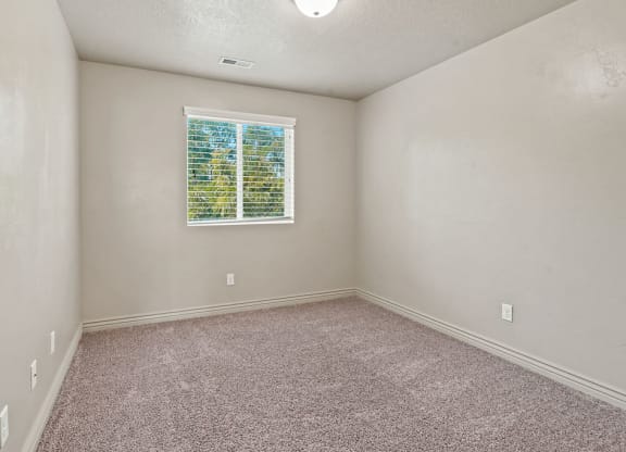 an empty room with a window and carpet