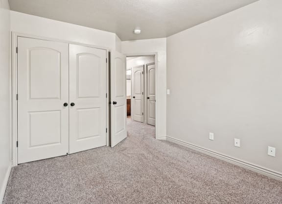 an empty bedroom with white doors and carpeting