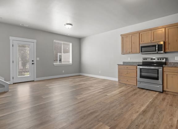 the kitchen and living room of a house with wood floors and stainless steel appliances