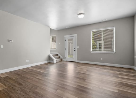 the living room is spacious and has a large window and hardwood floors
