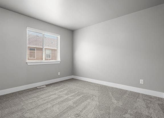 an empty room with a window and carpet