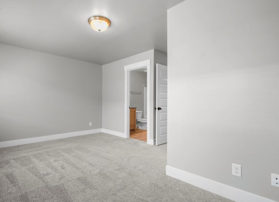a bedroom with a carpeted floor and a door to a bathroom
