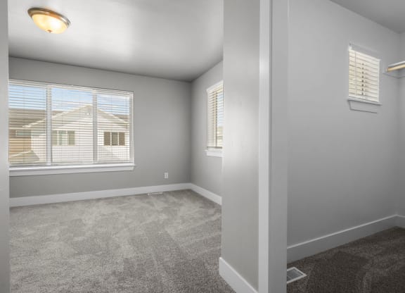 a bedroom with a large window and carpeted flooring