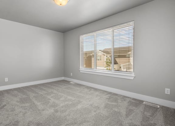 an empty living room with a window and carpet