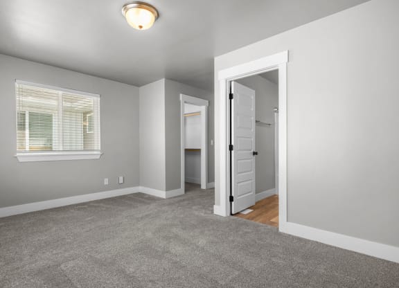 a bedroom with a door to a closet and a window