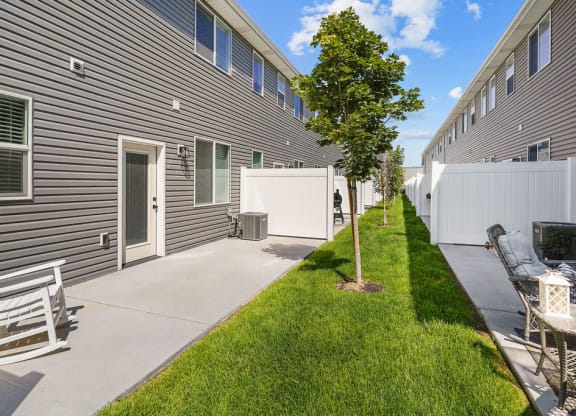 the yard of a home with a patio and a tree