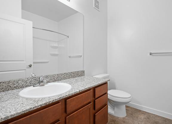 A white sink with a brown counter top and a white toilet in a bathroom.