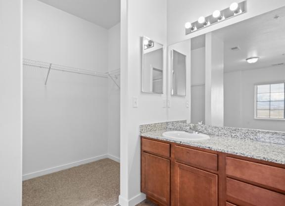 A bathroom with a sink, mirror, and a window.