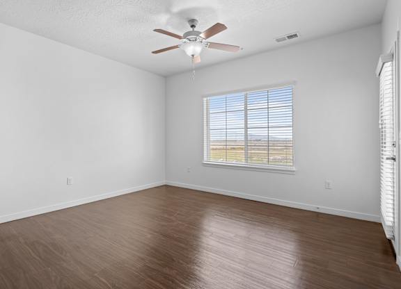 A room with a ceiling fan and a window with blinds.