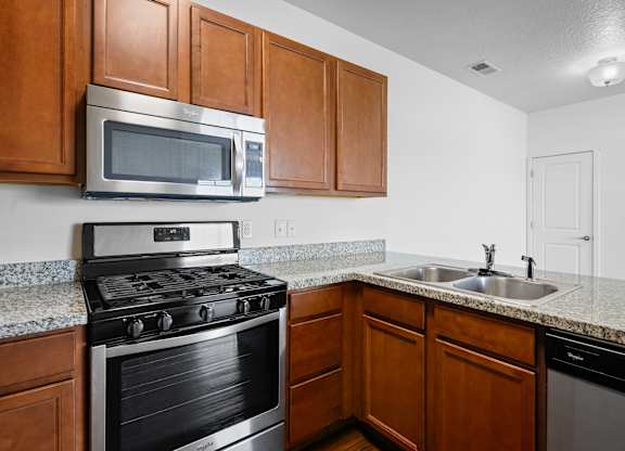 A kitchen with a stove, microwave, and sink.