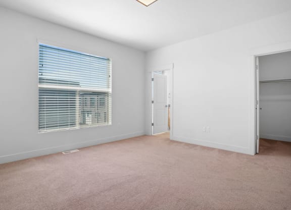 a bedroom with a large window and a door to a closet