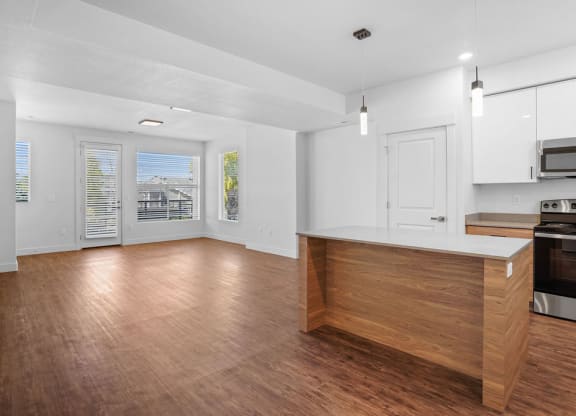 an empty kitchen and living room with wood floors and white walls