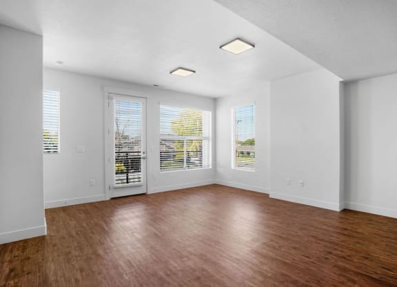 an empty living room with a hard wood floor and windows