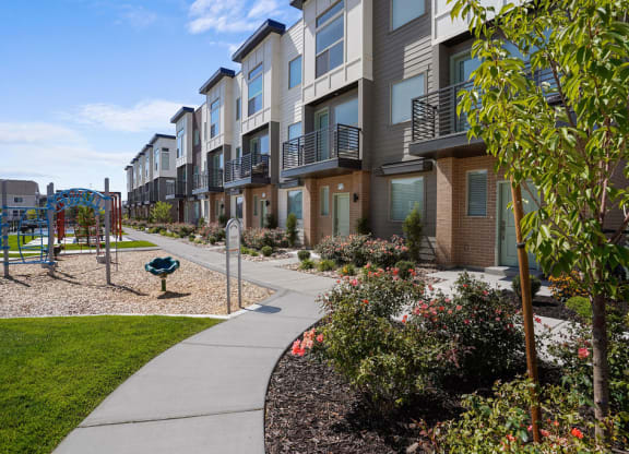 an exterior view of an apartment building with a playground and sidewalk