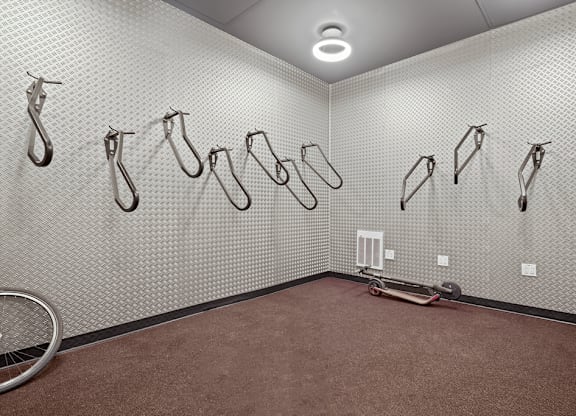 A room with a wall of hooks and a bicycle wheel on the floor.