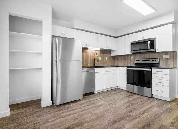 A kitchen with a refrigerator, oven, and microwave.
