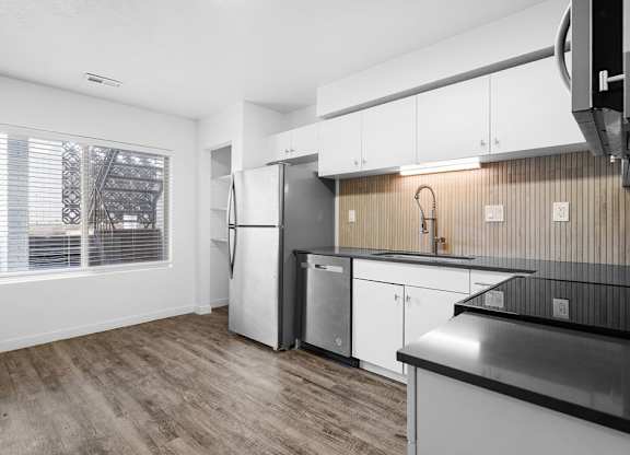 A kitchen with white cabinets and a black countertop.