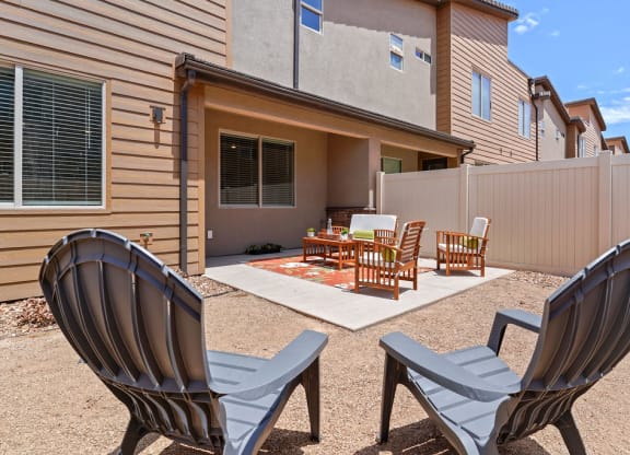a patio with chairs and a table in front of a house
