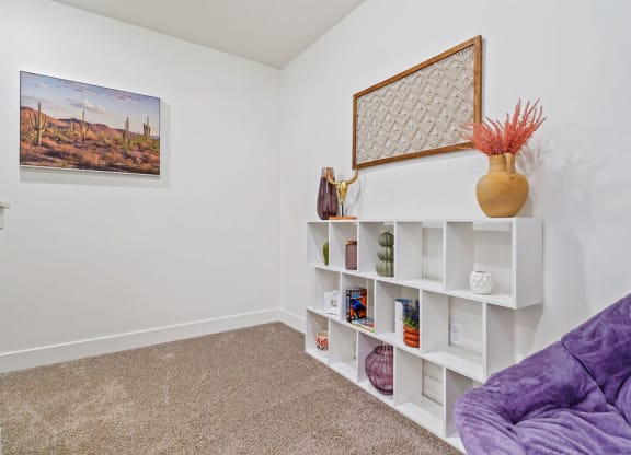 a living room with a purple couch and white shelves