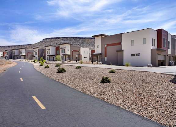 A road with a yellow line in the middle runs through a housing development.