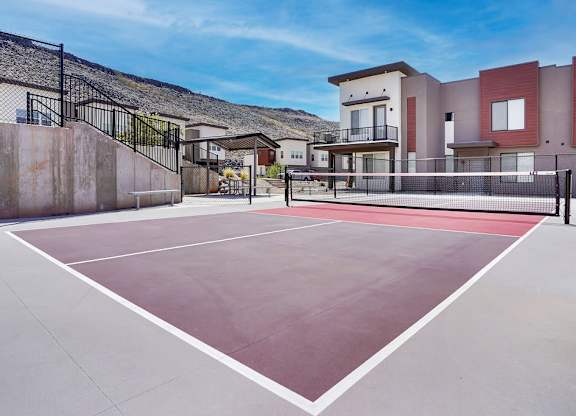 Tennis court in front of a building with a black fence.