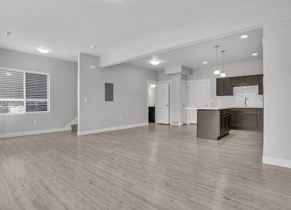 A spacious living room with a kitchen in the background.