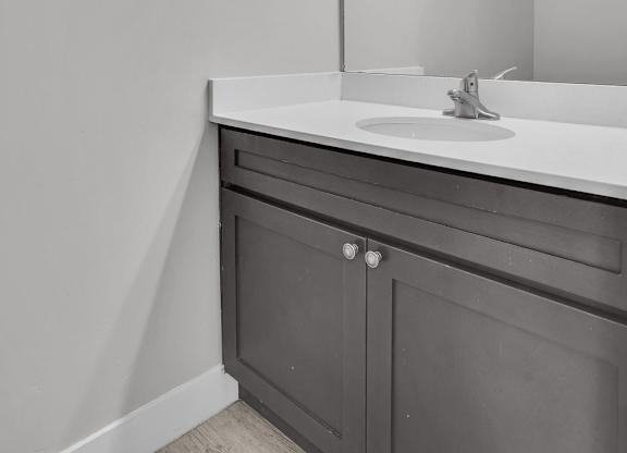 A bathroom with a white sink and a mirror with lights above it.
