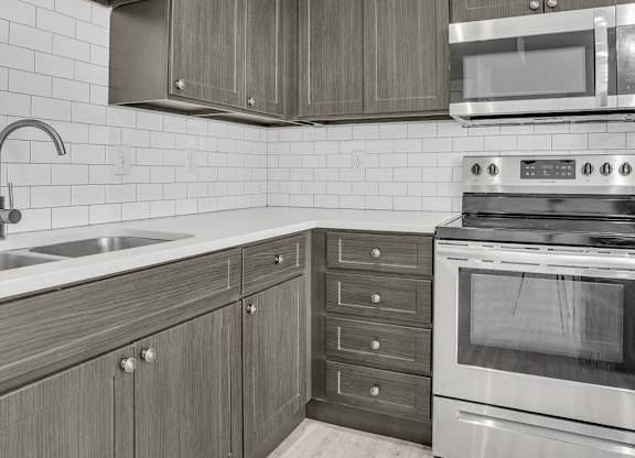 A kitchen with a stove, sink, and cabinets.