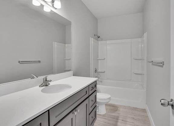 A white bathroom with a sink, mirror, and toilet.