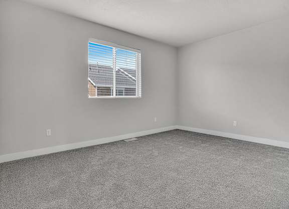 A room with a window showing a view of a house and a utility pole.