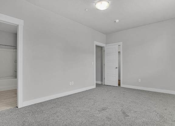 A room with a carpeted floor and two doors.