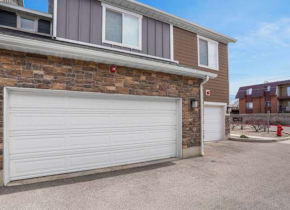 A garage door is closed in front of a brick wall.
