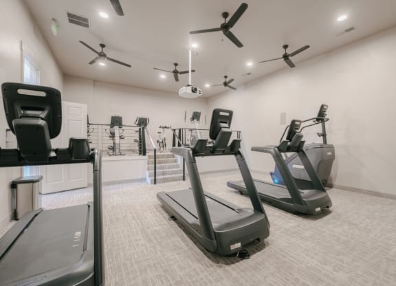 a gym with treadmills and other exercise equipment in a building with white walls at Aldara Apartments in Saratoga Springs, Utah