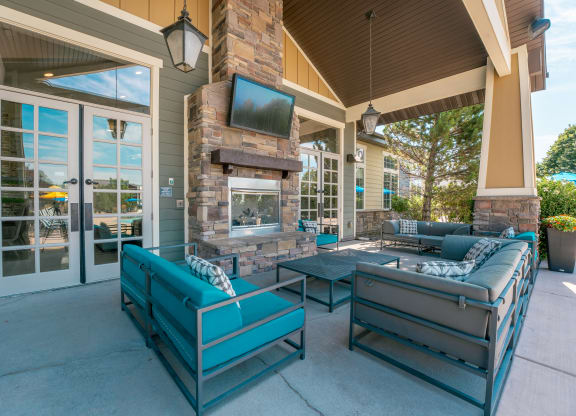 the preserve at ballantyne commons covered patio with furniture and a fireplace at Aldara Apartments in Saratoga Springs, Utah