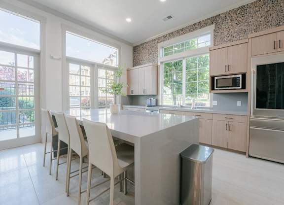 A kitchen with a large island and chairs.