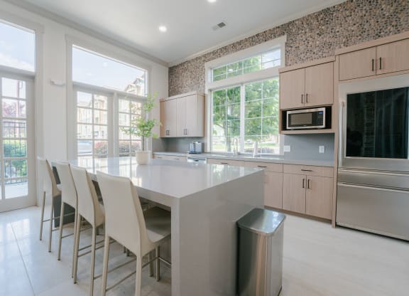a large kitchen with a large island with white chairs at Aldara Apartments in Saratoga Springs, Utah