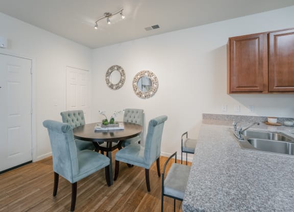 a dining room with a table and chairs and a kitchen with a sink at Aldara Apartments in Saratoga Springs, Utah