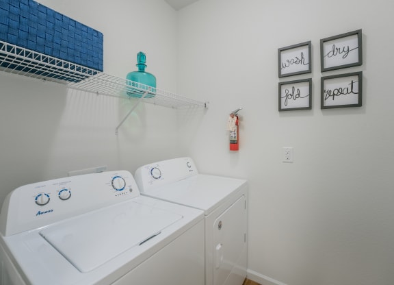 a washer and dryer in a laundry room with a shelf over the top at Aldara Apartments in Saratoga Springs, Utah