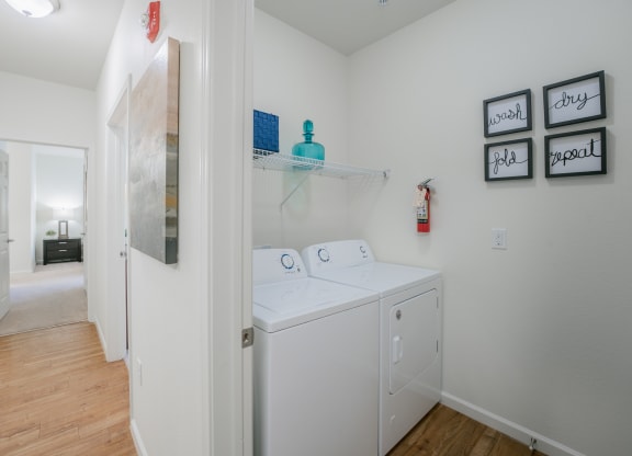 a laundry room with a washer and dryer and a hallway to a bathroom at Aldara Apartments in Saratoga Springs, Utah