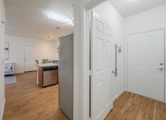 a renovated living room and kitchen with white walls and wood flooring at Aldara Apartments in Saratoga Springs, Utah