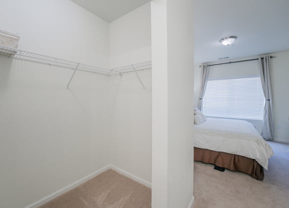 an empty bedroom with a bed and a closet with a window at Aldara Apartments in Saratoga Springs, Utah