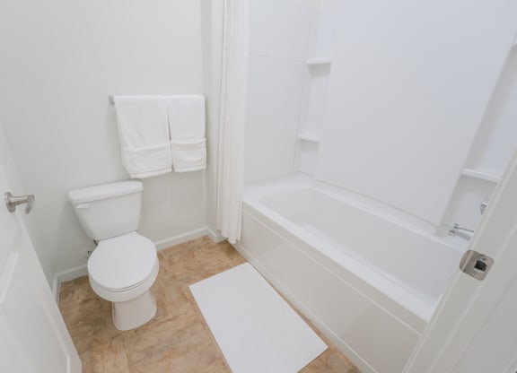a white bathroom with a toilet and a tub at Aldara Apartments in Saratoga Springs, Utah