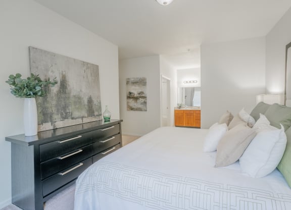a bedroom with a large white bed and a black dresser at Aldara Apartments in Saratoga Springs, Utah