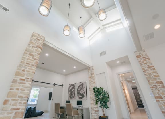 the living room and dining room in a modern home with exposed ceilings and brick columns at Aldara Apartments in Saratoga Springs, Utah