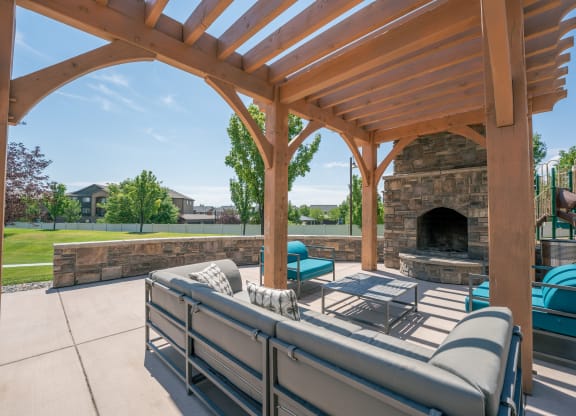 the outdoor living area has a patio with a fireplace and couches at Aldara Apartments in Saratoga Springs, Utah