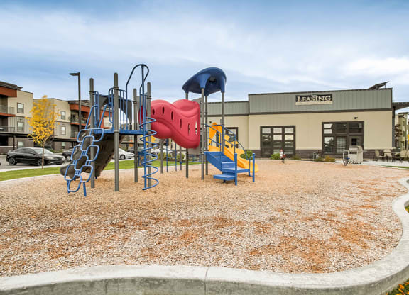 a playground in front of a building with a red and blue slide