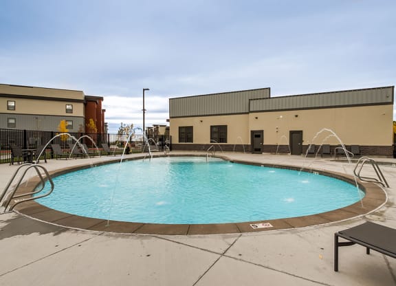a pool with water fountains and a building in the background