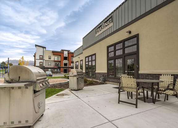 a patio with a grill and a table and chairs