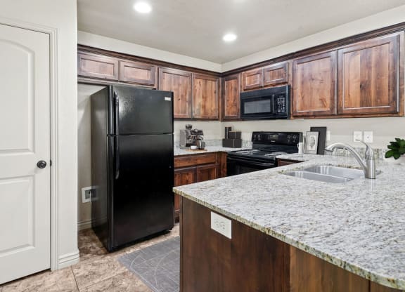 a kitchen with a granite counter top and a black refrigerator