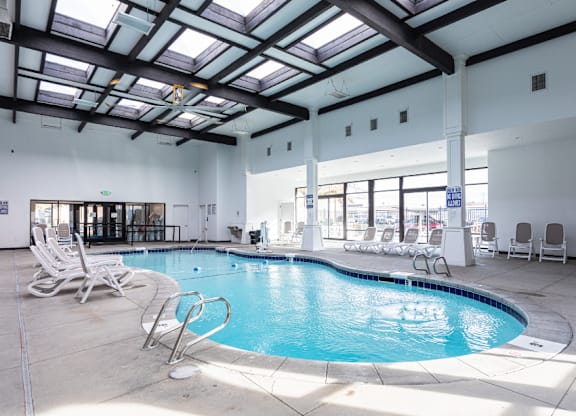 A large indoor swimming pool with sun loungers.